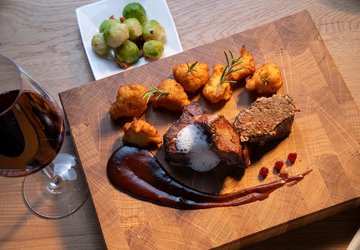 Ein Gericht vom Wild serviert auf einem Holzbrett mit Wein