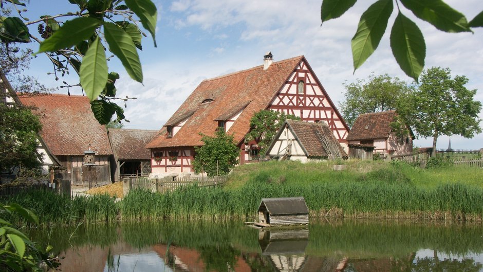 ©Fränkisches Freilandmuseum Ein großes Fachwerkhaus am Weiher im Fränkischen Freilandmuseum Bad Windsheim.