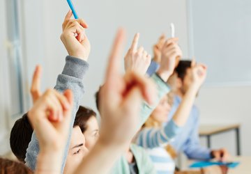 Mehrere Personen melden sich mit dem Finger in der Luft.