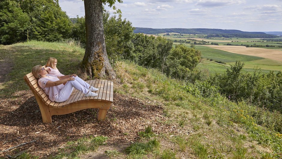 ©Ines Männl Frau ruht sich auf einer Bank aus und sieht in weite Landschaft hinaus